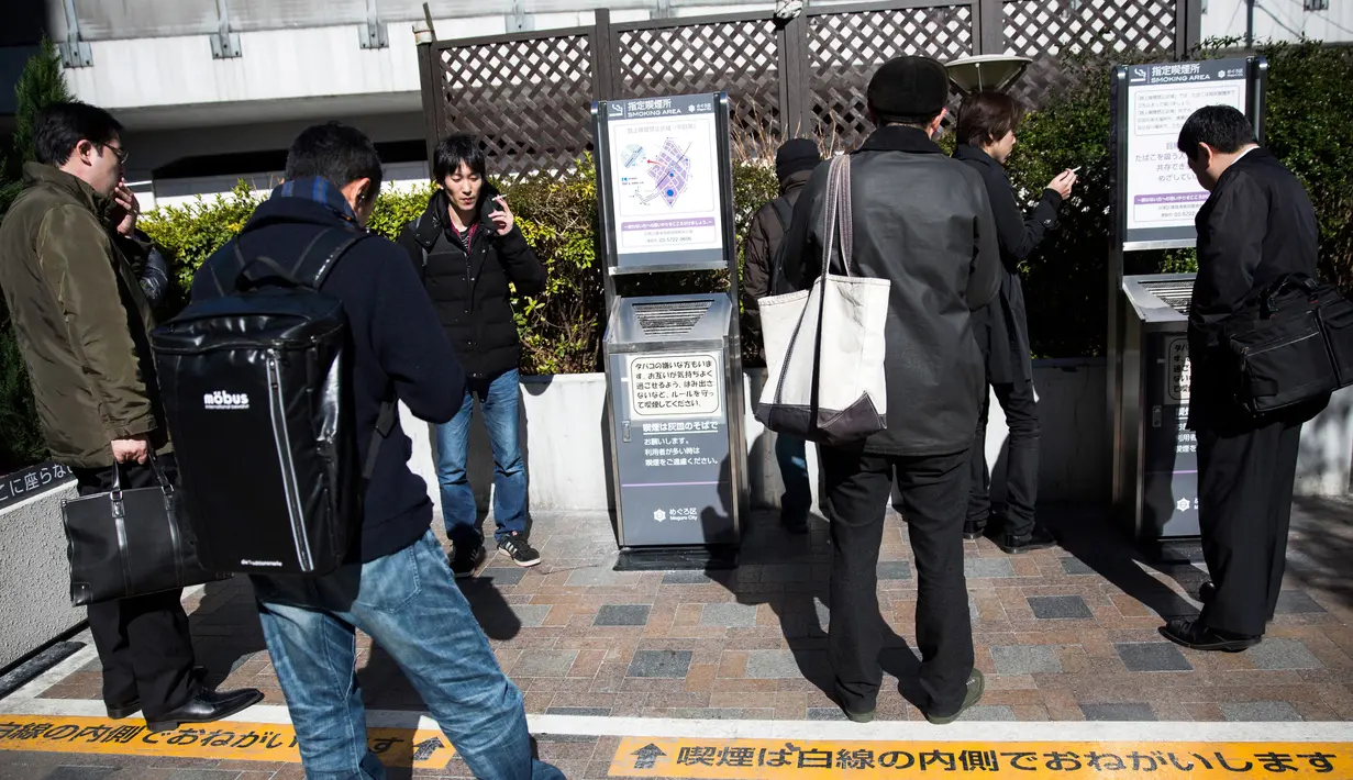 Sejumlah perokok berkumpul di smoking area yang disediakan di Naka-Meguro, Tokyo (10/3). Kesadaran warga Jepang termasuk tinggi dengan tertibnya para perokok yang tidak merokok di sembarang tempat. (AFP Photo/BEHROUZ MEHRI)