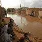 Penduduk Sudan duduk di luar rumah mereka yang banjir di daerah alqamayir di kota kembar ibu kota Omdurman (26/8/2020). (AFP Photo/Ashraf Shazly)