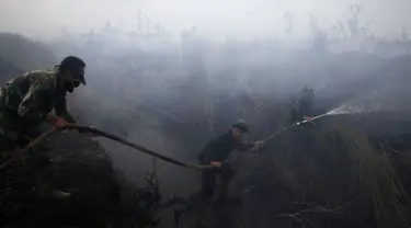 Anggota TNI memadamkan api di perkebunan kelapa sawit di Desa Padamaran, Ogan Komering Ilir , Sumatera Selatan, Sabtu (12/9/2015). Kebakaran lahan menyebabkan kabut asap di sejumlah wilayah dan mengganggu jadwal penerbangan. (REUTERS/Beawiharta)