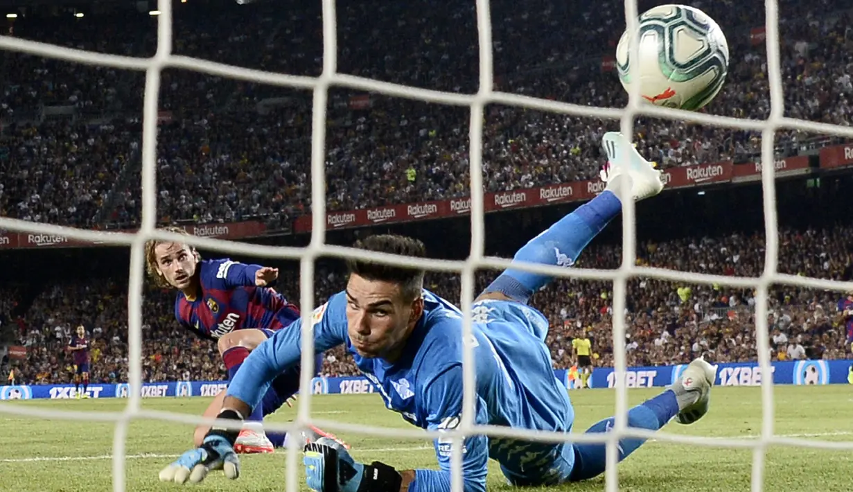 Penyerang Barcelona, Antoine Griezmann saat mencetak gol ke gawang Real Betis yang dijaga kiper Daniel Martin selama pertandingan La Liga Spanyol di stadion Camp Nou (25/8/2019). Griezmann mencetak dua gol di pertandingan ini dan mengantar Barcelona menang 5-2 atas Betis. (AFP Photo/Josep Lago)