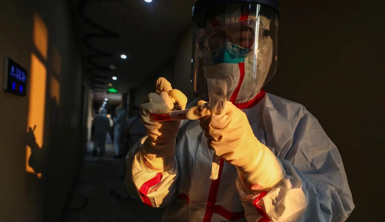 Pekerja medis berpakaian pelindung menulis pada sebuah tabung setelah mengumpulkan sampel untuk tes asam nukleat dari pasien yang diduga terinfeksi virus corona di hotel yang digunakan dalam isolasi medis virus corona di Wuhan, Provinsi Hubei, China, Selasa (4/2/2020). (Chinatopix via AP)