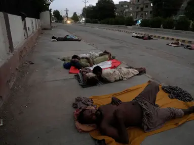 Para pekerja tidur di pinggir jalan pada pagi hari yang panas di awal musim panas di Karachi, Pakistan, Rabu, 29 Mei 2024. (AP Photo/Fareed Khan)