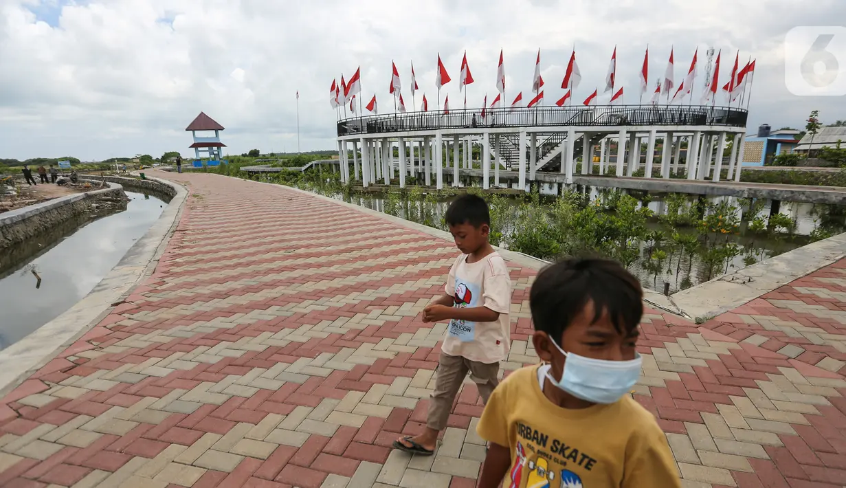 Anak-anak melintas di kawasan Gerbang Mapan Aquaculture di Desa Ketapang, Mauk, Kabupaten Tangerang (21/01/2022). Gerbang Mapan salah satu dari 15 program unggulan Kabupaten Tangerang yang digagas Wakil Presiden PEMSEA dan Network of Local Governments Ahmed Zaki Iskandar.(Liputan6.com/Fery Pradolo)