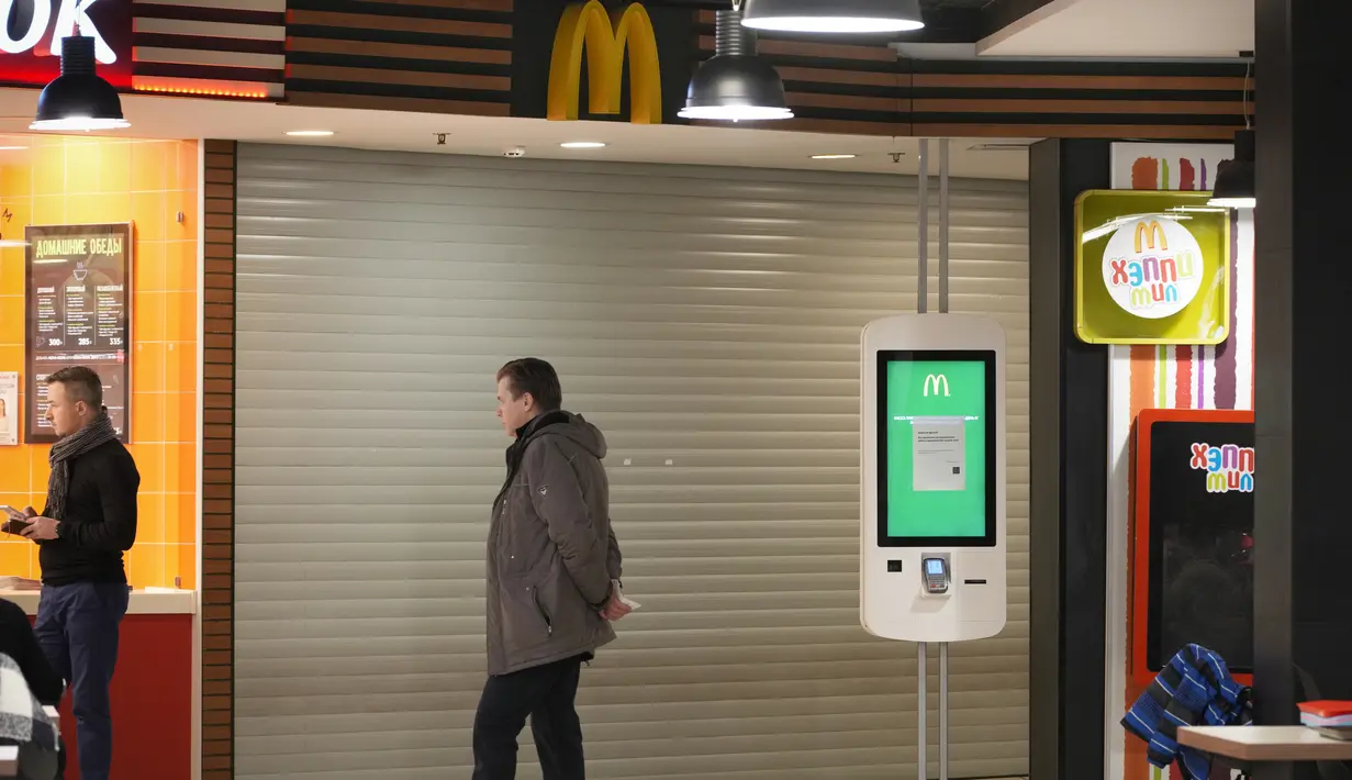 Seorang pria berdiri di sebelah restoran McDonald's yang tertutup untuk pengunjung di sebuah mal di St. Petersburg, Rusia, Selasa (15/3/2022). Gerai makanan siap saji McDonald's resmi menutup 850 gerainya yang beroperasi di Rusia pada 14 Maret 2022. (AP Photo)
