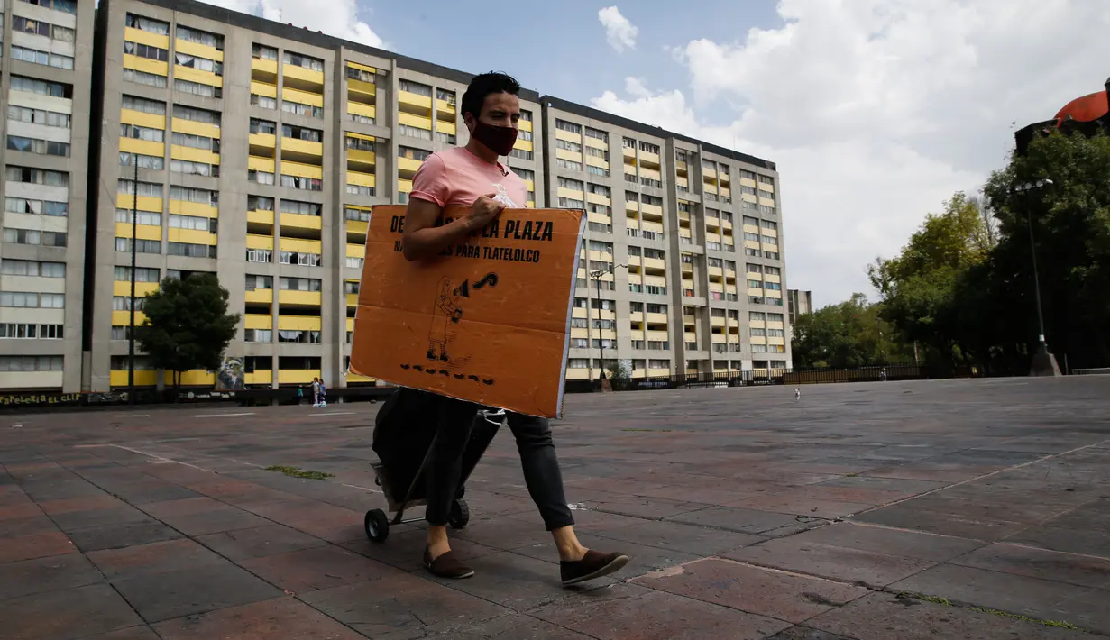 Percibald Garcia, pembaca cerita untuk anak-anak, menarik pengeras suara saat akan mendongeng di antara gedung-gedung di Mexico City pada 18 Juli 2020. Di tengah lockdown, Garcia hampir setiap hari mendatangi kompleks perumahan Tlatelolco untuk bercerita menghibur anak-anak. (AP/Marco Ugarte)