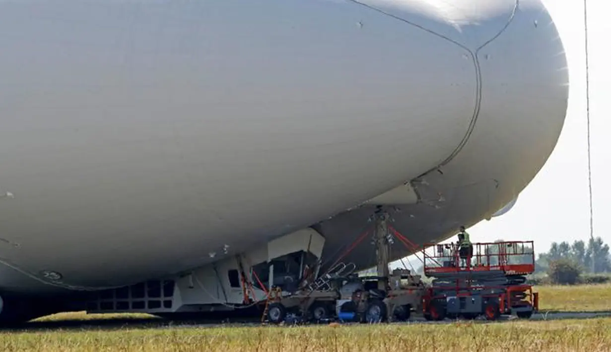 Pekerja meninjau kerusakan pesawat Airlander 10 yang gagal mendarat di Cardington Airfield, Inggris, Rabu (24/8). Pesawat yang diklaim terbesar di dunia itu rusak karena harus menukik tajam ketika melakukan pendaratan (REUTERS/Darren Staples)