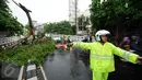 Petugas kepolisian mengatur arus lalu lintas yang tersendat akibat terhalang batang pohon yang jatuh tepat di tengah Jalan Kemang Raya, Jakarta, Sabtu (7/11/2015). Tidak ada korban dalam peristiwa ini. (Liputan6.com/Helmi Fithriansyah)