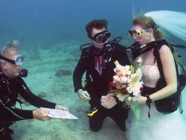 Pendeta John Hauk (kiri) membacakan sumpah pernikahan di bawah laut kepada pasangan Sersan Thomas Mould (tengah) dan Sandra Hyde dari Key Largo, Fla di Florida Keys National Marine Sanctuary (21/12). (Frazier Nivens/Florida Keys News Bureau via AP)