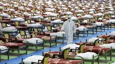 Petugas berpakaian pelindung berjalan melewati deretan tempat tidur di rumah sakit sementara khusus pasien virus corona COVID-19 di Teheran, Iran, Kamis (26/3/2020). Rumah sakit sementara yang dibangun di pusat pameran internasional ini memiliki 2.000 tempat tidur. (AP Photo/Ebrahim Noroozi)