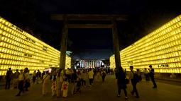 Sejumlah pengunjung melihat lentera yang memeriahkan Festival Mitama di Kuil Yasukuni, Tokyo, Jepang, (13/7). Sekitar 30.000 lentera menerangi daerah terseubt untuk mengenang korban perang.  (AFP Photo/Toru Yamanka)