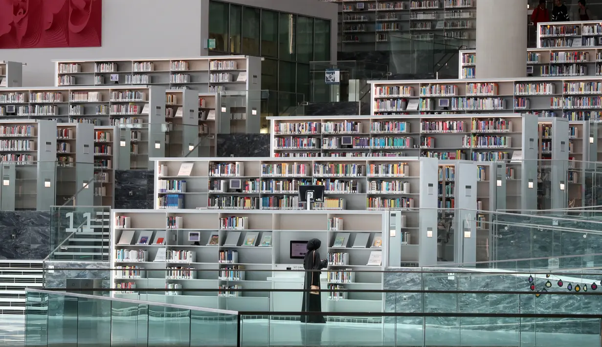 Seorang wanita melihat-lihat koleksi buku di Perpustakaan Nasional Qatar di ibu kota Doha pada 19 Mei 2019. Bangunan megah karya arsitek Rem Koolhaas ini memiliki luas 45 ribu meter persegi. (KARIM JAAFAR / AFP)
