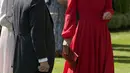 <p>Kate juga memadukan gaunnya dengan clutch bag merah dari Hermes dan sepatu pump suede merah.(AP Photo/Alastair Grant)</p>