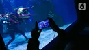 Pengunjung mengambil gambar atraksi Liong di Jakarta Aquarium & Safari (JAQS), Jakarta Barat, Jumat (12/2/2021). Pertunjukan Liong Show bawah air yang diikuti oleh para putri duyung tersebut untuk memeriahkan Hari Raya Imlek 2572 atau Tahun Baru China. (Liputan6.com/Faizal Fanani)
