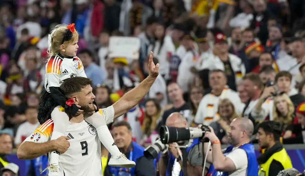 Pemain Jerman, Niclas Fullkrug merayakan kemenangan atas Skotlandia bersama putrinya setelah laga pembuka Grup A Euro 2024 di Allianz Arena, Munchen, Jerman, Sabtu (15/06/2024) WIB. (AP Photo/Frank Augstein)
