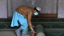 Umat Muslim menggulung karpet sajadah dari aula utama masjid menyusul pembatasan baru pemerintah baru menjelang bulan suci Ramadan di Rawalpindi, Pakistan, Senin (5/4/2021). Salat akan dilakukan di  halaman di masjid dan bukan di dalam aula. (Aamir QURESHI/AFP)
