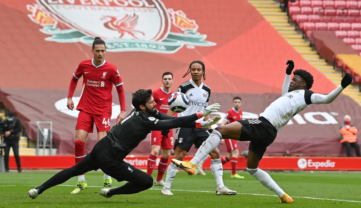 Kiper Liverpool, Alisson Becker (kiri) berusaha menangkap bola dari ancaman striker Fulham, Josh Maja dalam laga lanjutan Liga Inggris 2020/21 di Anfield Stadium, Minggu (7/3/2021). Liverpool kalah 0-1 dari Fulham. (AFP/Paul Ellis/Pool)