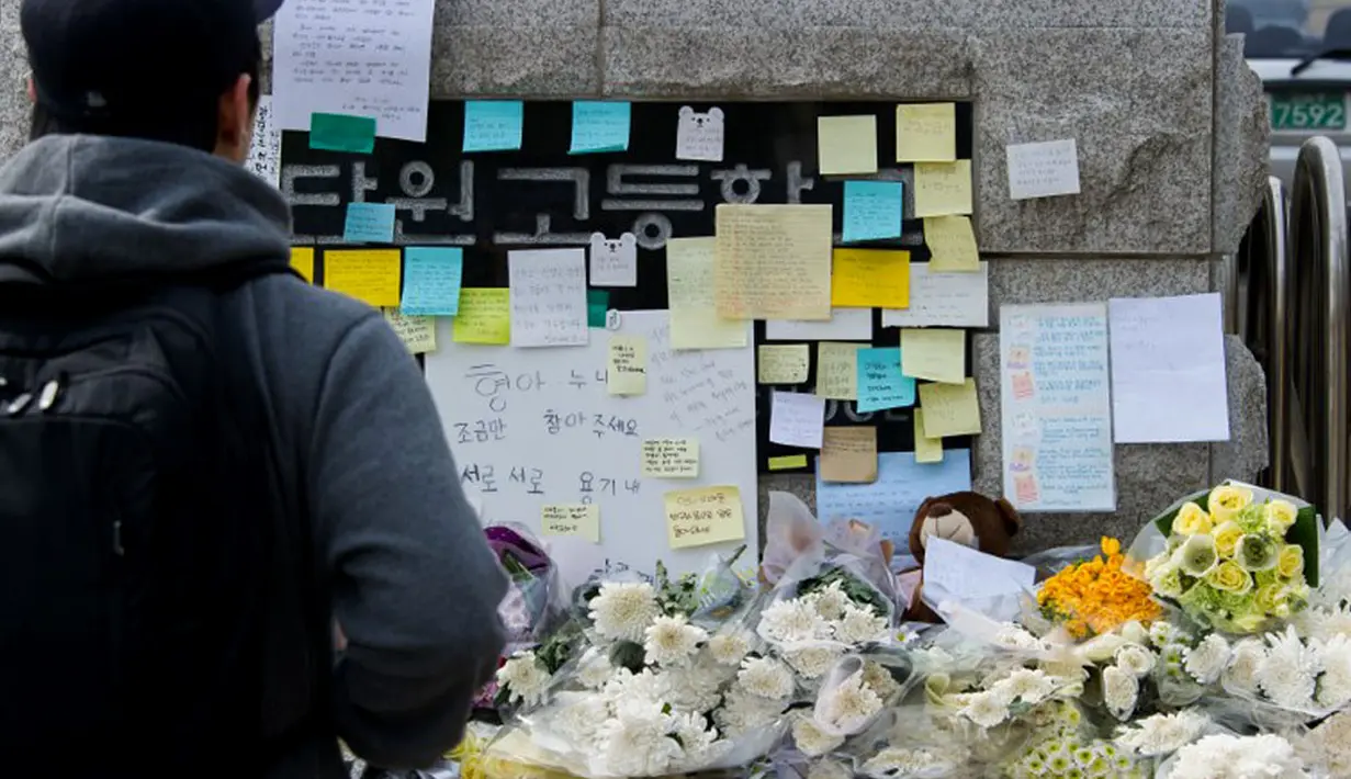 Seorang pria melihat-lihat karangan bunga dan pesan yang diletakkan di depan gerbang utama Ansan Danwon High School, Korea Selatan, Senin (21/4/2014). (AFP PHOTO/KIM DOO-HO)