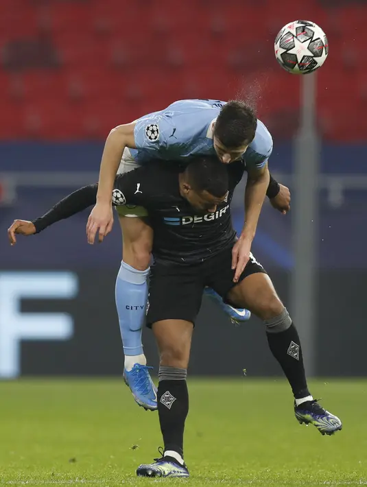 Bek Manchester City, Ruben Dias melompat untuk menyundul bola saat bersaing dengan penyerang Alassane Plea pada leg pertama 16 besar Liga Champions di Puskas Arena, Kamis (25/2/2021) dini hari WIB. Man City tekuk tuan rumah Borusia Monchengladbach 2-0. (AP Photo/Laszlo Balogh)