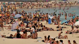 Pengunjung berjemur di pantai Bondi ketika pantai Bondi ketika suhu udara melonjak di Sydney (21/12/2019). Australia terganggu akibat bencana ganda yakni gelombang panas dan kebakaran hutan serta lahan di kawasan tersebut. (AFP/Farooq Khan)