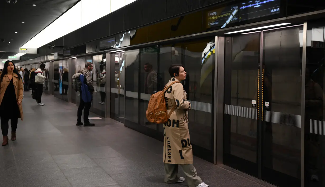 Para penumpang menunggu di Stasiun Canary Wharf Elizabeth Line yang baru dibuka di London Timur, Inggris, Senin (7/11/2022). Elizabeth Line akan mengantarkan penumpang langsung ke pusat Kota London dari Stasiun Reading, Heathrow, dan Shenfield. (Daniel LEAL / AFP)