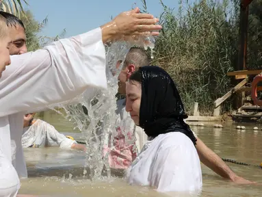 Pendeta membaptis umat Kristen di Sungai Yordan, Jericho, Palestina, Jumat (13/9/2019). Situs religi ini sejak tahun 1967 dikenal dengan nama dalam bahasa Arab Qasr al-Yahud. (HAZEM BADER/AFP)