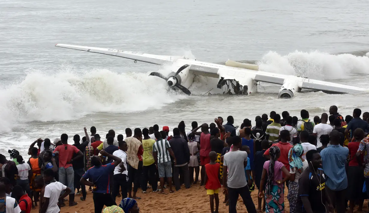 Warga berkumpul melihat pesawat kargo Antonov yang jatuh di lepas pantai Port-Bouet, Abidjan (14/10). Pesawat yang membawa 10 penumpang dihantam ombak besar Pantai Gading dan menewaskan 4 orang warga Moldovan. (AFP PHOTO / Sia KAMBOU)