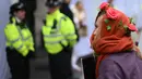 Seorang aktivis iklim yang mengenakan mahkota mawar ikut serta dalam protes menentang proyek ladang minyak Rosebank di Laut Utara di lepas pantai Skotlandia, di luar InterContinental London Park Lane, London, 18 Oktober 2023. (Daniel LEAL/AFP)