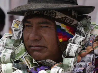 Seseorang berpakaian seperti Ekeko, Dewa Kemakmuran, diselimuti uang palsu pada hari pembukaan Pameran Alasita tahunan, di mana Ekeko adalah tokoh utamanya di El Alto, Bolivia, Selasa (24/1/2023). Orang-orang membeli replika kecil dari hal-hal yang ingin mereka peroleh sepanjang tahun, seperti rumah, mobil, dan kekayaan. Kata Aymara "Alasita" berarti "belikan aku". (AP Photo/Juan Karita)