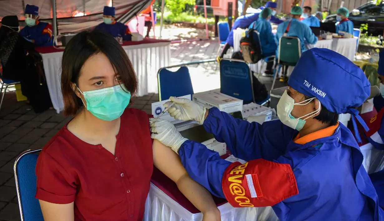 Seorang wanita menerima vaksin virus corona COVID-19 AstraZeneca di Denpasar, Bali, Sabtu (26/6/2021). Ratusan warga terlihat antusias mengikuti vaksinasi massal tersebut. (SONY TUMBELAKA/AFP)