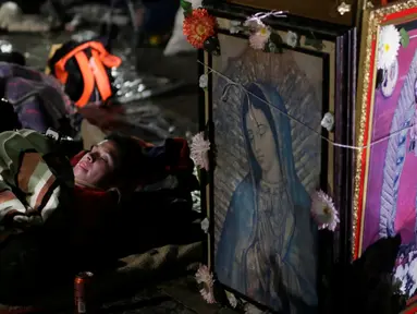 Seorang peziarah beristirahat di samping gambar Bunda dari Guadalupe di kawasan Basilika Guadalupe di Mexico City, Meksiko (11/12). Bunda dari Guadalupe dikenal juga dengan sebutan Our Lady of Guadalupe atau Virgin of Guadalupe. (Reuters/Henry Romero)