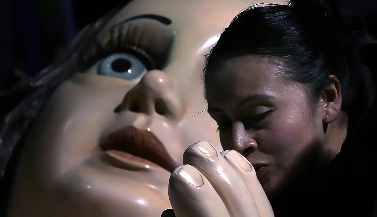 Seorang wanita mencium tangan patung bayi Yesus raksasa di Mexico City, Meksiko, Senin (23/12/2019). Patung tersebut dipersiapkan untuk menyambut malam Natal. (AP Photo/Marco Ugarte)