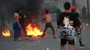 Demonstran antipemerintah bentrok dengan pasukan keamanan saat protes di dekat Alun-Alun Tahrir, Baghdad, Irak, Senin (27/7/2020). Perdana Menteri Irak mengatakan telah memerintahkan penyelidikan atas pembunuhan dua demonstran antipemerintah. (AP Photo/Hadi Mizban)