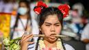 Seorang wanita menusuk pipinya dengan batang daun saat mengikuti prosesi perayaan Festival Vegetarian tahunan di Phuket, Thailand, Kamis (3/10/2019). Festival menyiksa diri ini dipercaya bagi warga Phuket akan mendapat kesehatan dan ketenangan pikiran. (AFP Photo/Mladen Antonov)