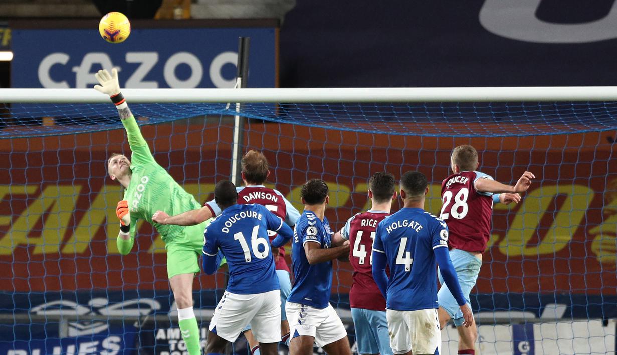Kiper Everton, Jordan Pickford (kiri) terbang menepis tandukan gelandang West Ham United, Tomas Soucek (kanan) dalam laga lanjutan Liga Inggris 2020/21 pekan ke-17 di Goodison Park, Jumat (1/1/2021). Everton kalah 0-1 dari West Ham United. (AFP/Jan Kruger/Pool)