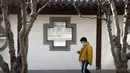 Seorang pria mengenakan masker melihat smartphone-nya saat dia berjalan di taman umum di Beijing, Rabu (5/1/2022). China melaporkan penurunan besar infeksi COVID-19 lokal di kota utara Xi'an, yang telah dikunci ketat selama dua minggu terakhir. (AP Photo/Mark Schiefelbein)
