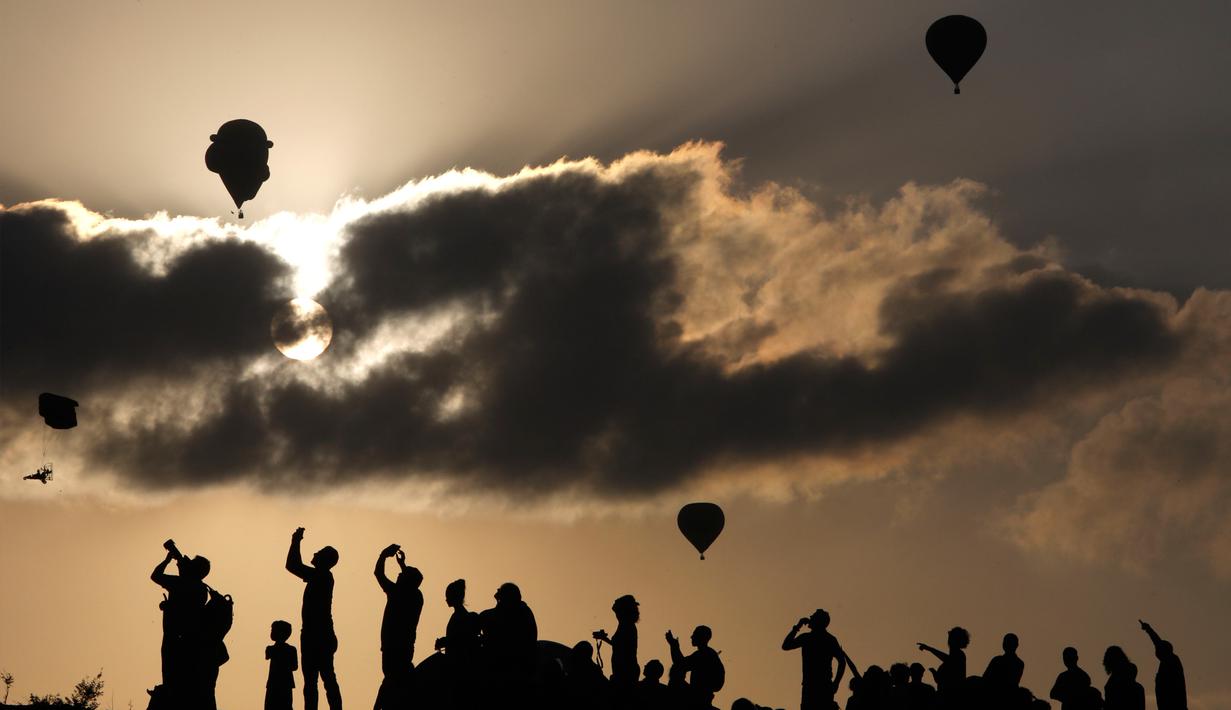 Pengunjung menyaksikan Festival Balon Udara Gilboa di dekat Kibbutz Ein Harod, Lembah Jizreel, Israel (4/8). Acara ini juga dimeriahkan dengan pertunjukan paragliders, paramotor dan karya para seniman udara. (AFP Photo/Manahem Kahana)
