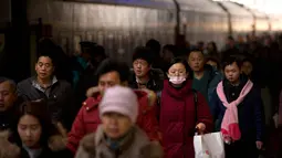 Warga berjalan ke sebuah kereta di Stasiun Kereta Api Beijing, (9/2). Sambut perayaan Imlek 2018, Jutaan warga China mulai memenuhi stasiun, bandara dan jalan yang diperkirakan akan dimulai akhir pekan ini. (AP Photo / Mark Schiefelbein)