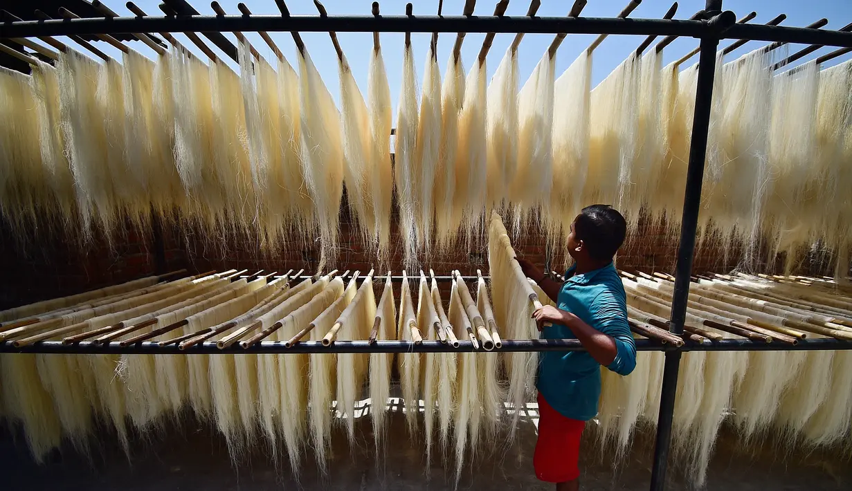 Pekerja menjemur bihun yang digunakan dalam hidangan manis tradisional yang populer dikonsumsi selama bulan suci Ramadhan di sebuah pabrik di Allahabad, India (13/4/2021). (AFP Photo/Sanjay Kanojia)