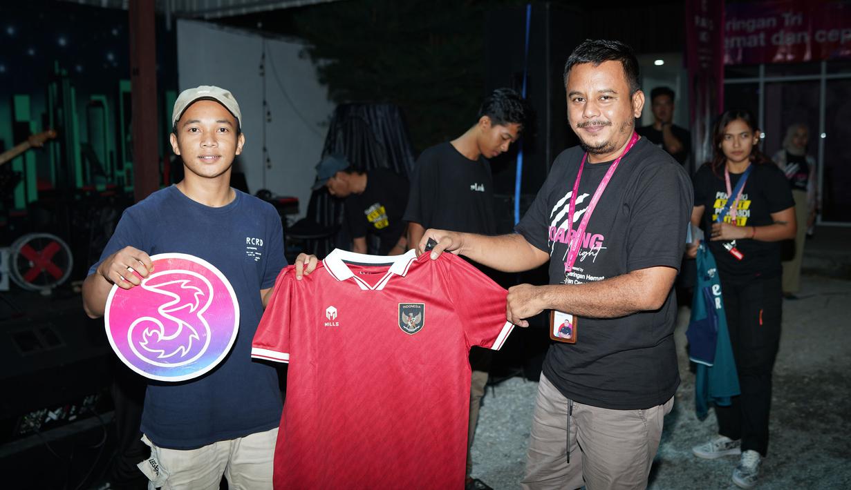 Seorang pemenang games berfoto dengan hadiah berupa jersey Tim Nasional Indonesia dalam acara nonton bareng Liga Inggris bertajuk Roaring Night yang dipersembahkan oleh jaringan hemat dan cepat Tri di Kafe Stay With Me, Pangkalpinang, Sabtu (11/11/2023). (Istimewa)