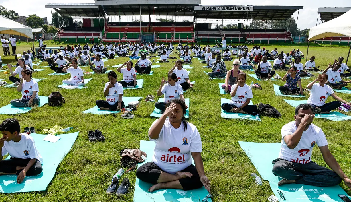 Ratusan warga melakukan gerakan yoga saat mengikuti sesi yoga massal di Stadion Afraha di Nakuru, Kenya (15/6/2019). Acara yoga massal ini untuk memperingati Hari Yoga Internasional. (AFP Photo/Suleiman Mbatiah)