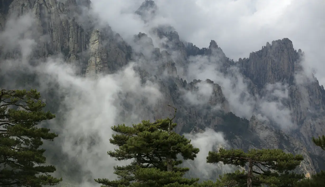 Puncak Bavella yang dikelilingi oleh awan di dekat Zonza, selatan Pulau Corsica, Prancis, Rabu (25/8/2021). Situs Bavella penuh sesak dengan turis selama musim panas. (AFP/Pascal Pochard-Casabianca)