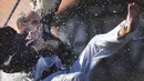 Seorang pemuda bergelayutan pada sebuah tali dengan hanya berpegangan pada kepala seekor angsa mati pada Hari angsa atau Antzar Eguna di Spanyol, Minggu (6/9/2015). Acara ini pernah dikecam oleh para aktivis binatang. (REUTERS/Vincent West)