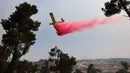 Sebuah pesawat pemadam kebakaran bekerja memadamkan kebakaran hutan yang berkobar di dekat kibbutz Maale Hahamisha di daerah desa Arab-Israel Abu Ghosh dekat Yerusalem, Israel, Rabu (9/6/2021). Puluhan petugas pemadam kebakaran dan 10 tanker udara berjuang memadamkan api. (Menahem KAHANA/AFP)