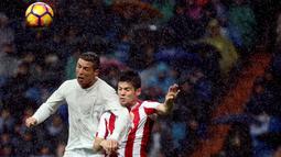 Penyerang Real Madrid, Cristiano Ronaldo, duel udara dengan pemain Sporting Gijon, Jorge Mere. Pada laga ini kedua gol Los Blancos dicetak oleh CR 7. (Reuters/Susana Vera)