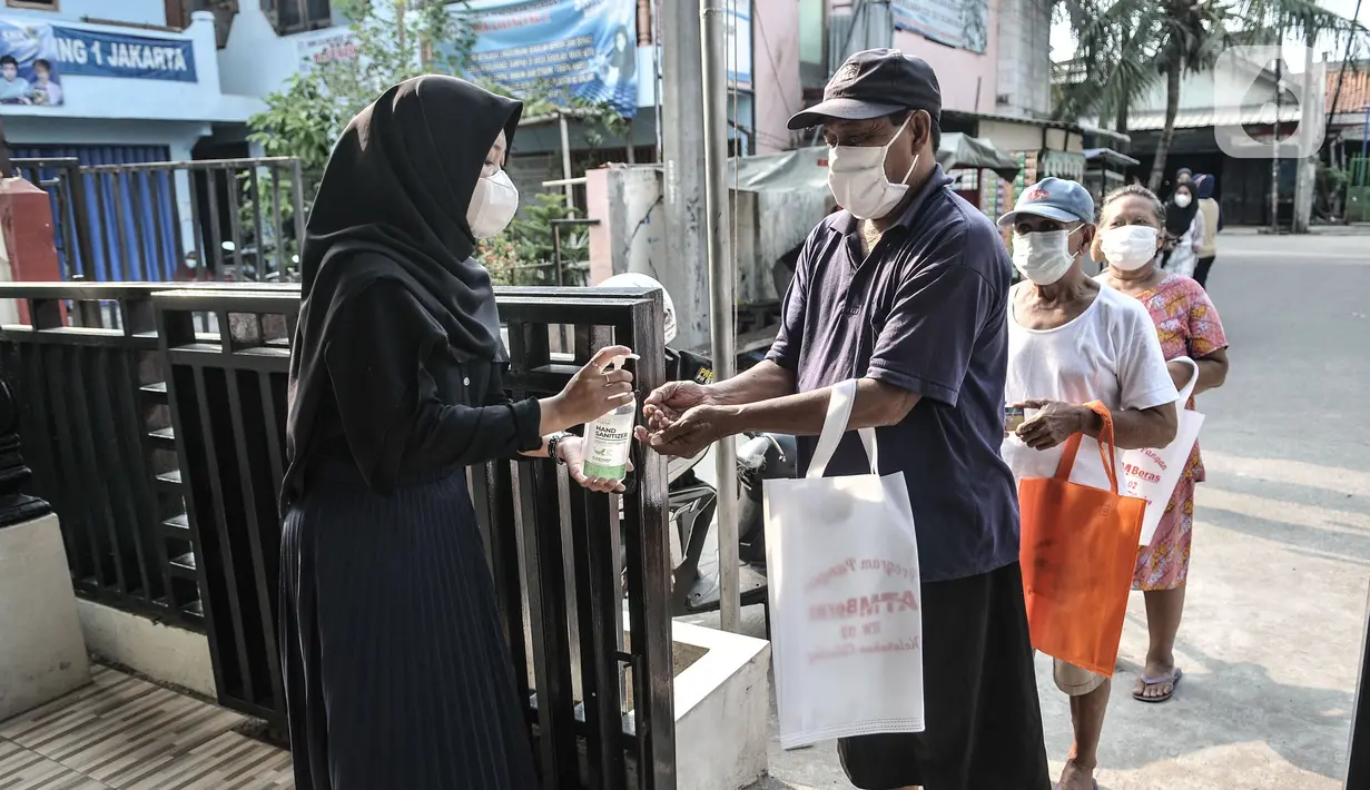 Warga lansia mencuci tangan untuk menerima bantuan beras di Kantor RW 02, Kelurahan Cilincing, Jakarta Utara, Rabu (17/3/2021). Warga di RW 02 Kelurahan Cilincing membuat ATM Beras secara mandiri yang kemudian dibagikan kepada lansia dan masyarakat tidak mampu. (merdeka.com/Iqbal S. Nugroho)