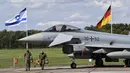 Bendera Israel dan Jerman terlihat di belakang jet Eurofighter, Noervenich, Jerman, Kamis (20/8/2020). Pilot Israel dan Jerman akan terbang bersama selama dua minggu ke depan selama latihan Angkatan Udara gabungan pertama di Jerman. (AP Photo/Martin Meissner)