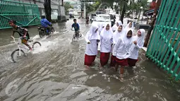Sejumlah anak berusaha menerobos banjir yang merendam Jalan Panjang, Jakarta Barat, Jumat (26/2). Hujan yang mengguyur wilayah Jakarta membuat sejumlah titik terendam banjir dengan ketinggian sekitar 20 cm hingga 1 meter. (Liputan6.com/ Immanuel Antonius)