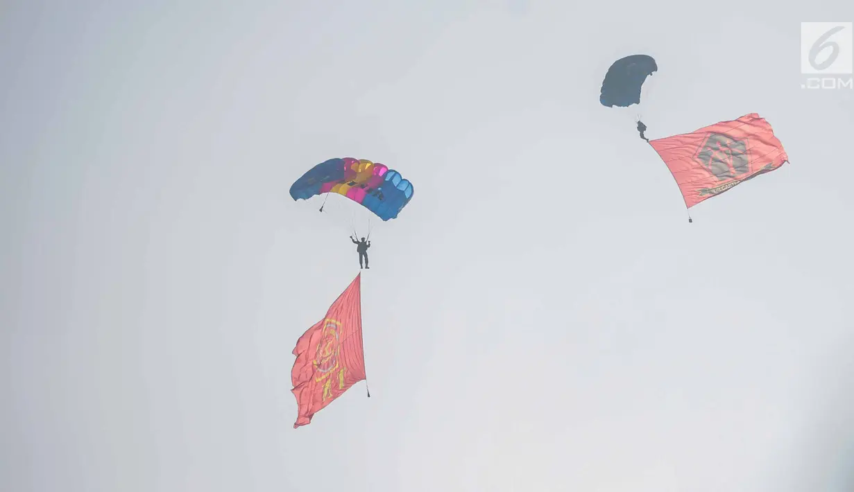 Penerjun payung mengibarkan bendera TNI dan Komando Operasi Khusus (Koopssus) TNI usai peresmian Koopssus TNI di Lapangan Markas Koopssus TNI, Jakarta, Selasa (30/7/2019). Koopssus TNI berasal dari matra darat, laut, dan udara. (Liputan6.com/Faizal Fanani)