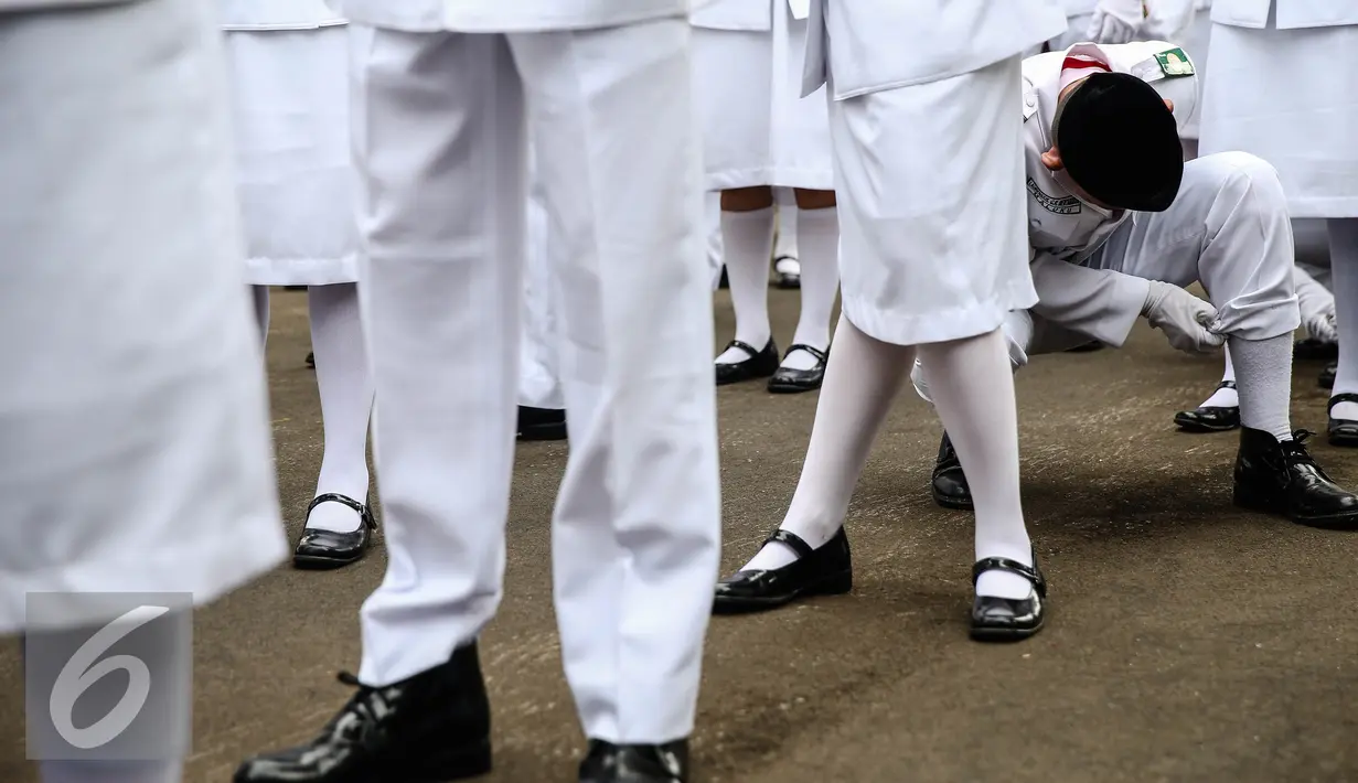 Anggota Paskibraka 2016 merapikan kaos kaki saat bersiap melaksanakan gladi bersih Upacara HUT ke-71 Kemerdekaan RI di Istana Merdeka, Jakarta, Senin (15/8). (Liputan6.com/Faizal Fanani)