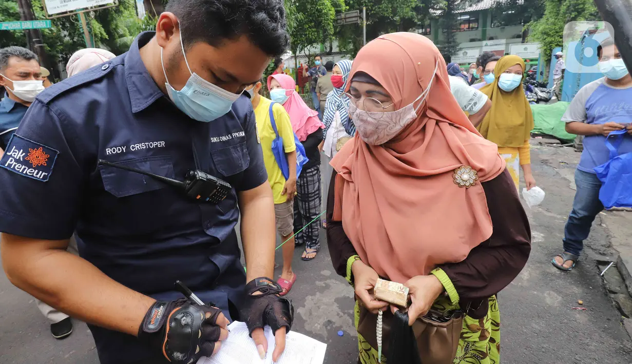 Petugas mendata warga yang mengantre minyak goreng murah di depan Kantor Kecamatan Johar Baru, Jakarta, Senin (17/1/2022). Sudin PPKUKM Jakarta Pusat menggelar Operasi Pasar minyak goreng murah dengan harga Rp 14.000 per liter. (Liputan6.com/Herman Zakahria)